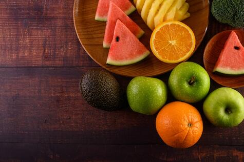 Free Photo | Watermelon, pineapple, oranges, cut into pieces with avocado, broccoli and apples on wood table. top view.