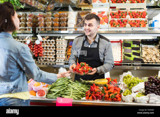 Male shop assistant is helping to buy fruit and vegetables in grocery shop Stock Photo - Alamy